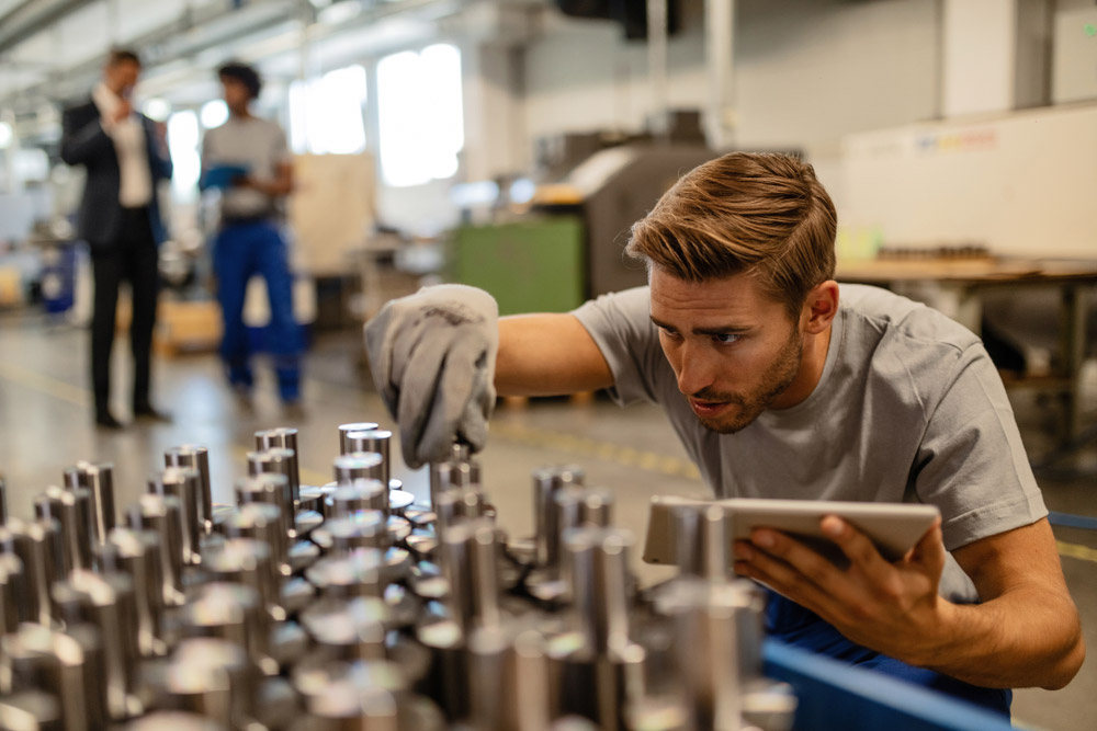 Young,Steel,Worker,Examining,Manufactured,Rod,Cylinder,While,Using,Digital